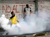 Un joven manifestante devuelve un bote de gas lacrimógeno a las fuerzas antidisturbios que protegen el palacio de Carandolet, en Quito.