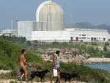 Dos bañistas pasean junto a la central nuclear de Vandellós II.
