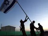 Soldados israelíes quitan la bandera israelí durante la ceremonia de clausura en la base militar cercana al asentamiento judío de Neve Dekalim, Franja de Gaza.