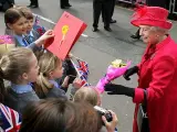 La reina Isabel II de Inglaterra coge el ramo de flores que una niña le regala, mientras camina por el centro de Windsor en el día en el que la monarca celebra su 80 cumpleaños.
