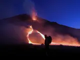 <strong>Anillo de fuego.</strong> Un turista pasa por delante del volcán Etna en Sicilia. Su actividad volcánica ha aumentado desde el pasado fin de semana.