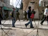 Niños palestinos pasan delante de soldados israelíes durante una operación militar en Hebron (Foto: Efe)