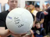 Un visitante muestra un balón de fútbol firmado por el presidente fundador de Microsoft Bill Gates.