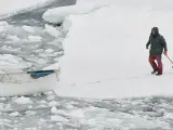Una foca muerta es arrastrada por su verdugo hacia una lancha en donde espera otro pescador.