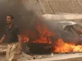 Un hombre pasa delante de uno de los coches incendiados por la explosión de un camión bomba en la ciudad de Kirkuk.