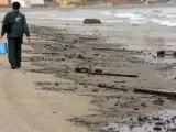 Un agente de la Guardia Civil recoge resíduos de hidrocarburo en la playa de la Concha, en Algeciras (A.Carrasco Ragel / EFE).