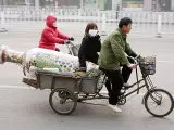 Una pareja de chinos transporta un jarrón por las calles de Pekín.