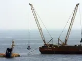 Varias grúas sacan chatarra de los depósitos del buque 'New Flame' que sigue encallado en la costa cerca de Gibraltar. (A.C.R./EFE)