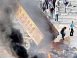 Varios manifestantes queman neumáticos y vacían un camión con arena y piedras en una calle de Beirut.