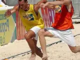 Dos jóvenes disputando un partido de fútbol playa