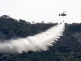Un helicóptero sobrevuela, vertiendo agua, la zona afectada por el incendio que se declaró ayer en Monte Pelayo. (EFE)