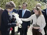 La Reina Sofía recibe un ramito de cerezo de manos de la propietaria de una finca, Carmen Gallego (d), en presencia del presidente de la Junta de Extremadura, Guillermo Fernández Vara.