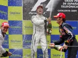 El piloto británico Jenson Button (c), de la escudería Brawn GP; su compañero de equipo, el brasileño Rubens Barrichello (i), y el australiano de Red Bull, Mark Webber, primero, segundo y tercero, respectivamente, celebran con champán sus puestos.