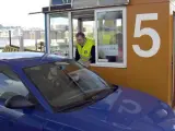 Un empleado cobra el peaje a un conductor.