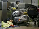 Pasajeros de Air Comet esperan con sus equipajes junto a los mostradores de facturación en Barajas.