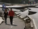 Varias personas transitan junto a una carretera destruida por el terremoto este sábado 27 de febrero en Santiago de Chile