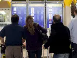 Pasajeros consultando la información de salida de vuelos en Barajas.