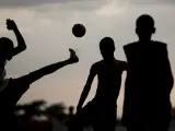 Varios niños juegan fútbol al caer la tarde.