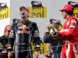 Mark Webber, piloto de Red Bull, celebra su triunfo bañado en champán por Fernando Alonso (Ferrari) con Vettel mirando.