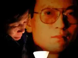 Fotografía de archivo de una activista llorando junto a una foto del disidente Liu Xiaobo