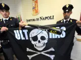 La policía italiana despliega una bandera y el material incautado a hinchas del Nápoles durante un enfrentamiento con seguidores del Liverpool.