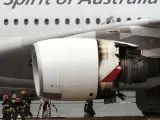 Los bomberos inspeccionan el Airbus A380 de la aerolínea australiana Qantas que tuvo que aterrizar de emergencia.