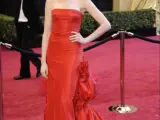 La actriz estadounidense Anne Hathaway posa la alfombra roja con un florido vestido rojo.