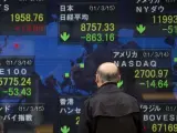 Unos hombres japoneses miran a una pantalla grande que muestra los resultados de varios bolsas internacionales en Tokio, Japón.