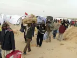 Trabajadores sudaneses que huyeron de Libia, transportan sus pertenencias en el campo de refugiados instalado junto a la frontera de Ras el Jedir (Túnez).