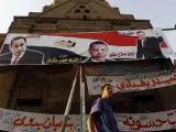 Foto de archivo de un hombre junto a un cartel electoral del Partido Nacional Democrático de Hosni Mubarak en El Cairo, Egipto.