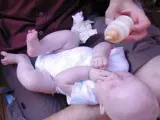 Un padre le da el biberón a su hijo.