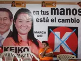 Una mujer permanece sentada delante de un cartel de Keiko Fujimori en Lima (Perú).