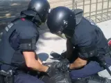 Dos mossos inmovilizan a un manifestante durante las protestas convocadas por el 15-M ante el Parlament en Barcelona.