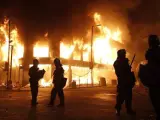 Varios bomberos frente a un edificio en llamas durante los disturbios que tuvieron lugar en Tottenham (Londres, Reino Unido).