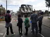 Un grupo de peatones observan los restos de una tienda de muebles incendiada en Croydon, Londres, Reino Unido.