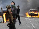 Un joven sujeta un juguete frente a un coche ardiendo, durante los enfrentamientos que se viven en el conflictivo barrio de Hackney, al este de Londres.