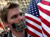 Uno de los manifestantes de Nueva York se tapa la boca con un billete de dólar.