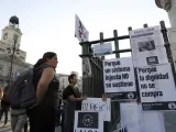 Varias personas observan los carteles colocados en la madrileña Puerta del Sol el 15-O.