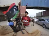 Un rebelde libio con una camiseta del club de f&uacute;tbol AC Milan en un punto de control hecho con contenedores entre Tr&iacute;poli y Misrata, en Libia.