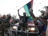 Ciudadanos libios dejan paso, en medio de un ambiente festivo, a un vehículo en el que los rebeldes que porta una bandera de "la nueva Libia".