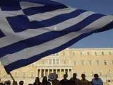 Manifestantes alzan una bandera frente al parlamento griego.