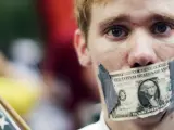 Un manifestante del movimiento 'Occupy Wall Street' se tapa la boca con un billete de dólar a modo de protesta junto al parque Zucotti Park, próximo al distrito financiero de nueva York.