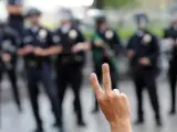 Manifestantes del movimiento "Indignados" hacen el signo de la victoria frente a una línea de policías el jueves 17 de noviembre de 2011, en la Plaza Bank of America de Los Ángeles (CA, EE.UU.). 23 personas fueron detenidas antes de que las autoridades lograran disolver la marcha y limpiar las calles.