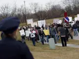 Un policía observa cómo un grupo de manifestantes avanza hacia la oficina en Iowa de la candidata republicana Michele Bachmann.