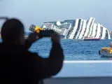 Un hombre saca una fotografía del crucero Costa Concordia, que encalló frente a las costas de la isla de Giglio, en Italia.