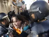 Varios agentes antidisturbios sujetan a una joven durante la marcha de este viernes por el centro de Valencia.