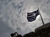 Fotografía de archivo tomada el 29 de junio de 2011 que muestra a un turista bajo la bandera griega en el Acrópolis de Atenas (Grecia).