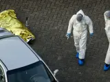 Policías inspeccionan un coche aparcado junto al cadáver de una de las víctimas del tiroteo en el comercial de Alphen aan den Rijn.