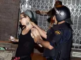 Un policía aparta a una chica durante el desalojo de los 'indignados' durnate la madrugada del lunes 14-M.