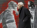 Un hombre pasa por delante de un cierre pintado en Atenas, Grecia. Las pintadas y los grafitis hacen alusión a la profunda crisis y la situación social que afecta a Grecia.
